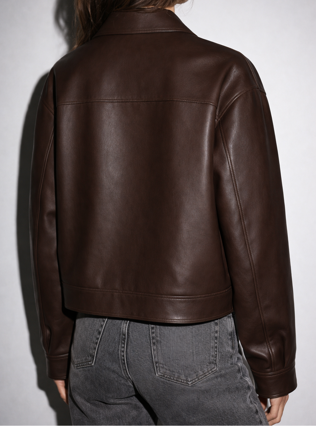 Person wearing a brown leather jacket against a white background