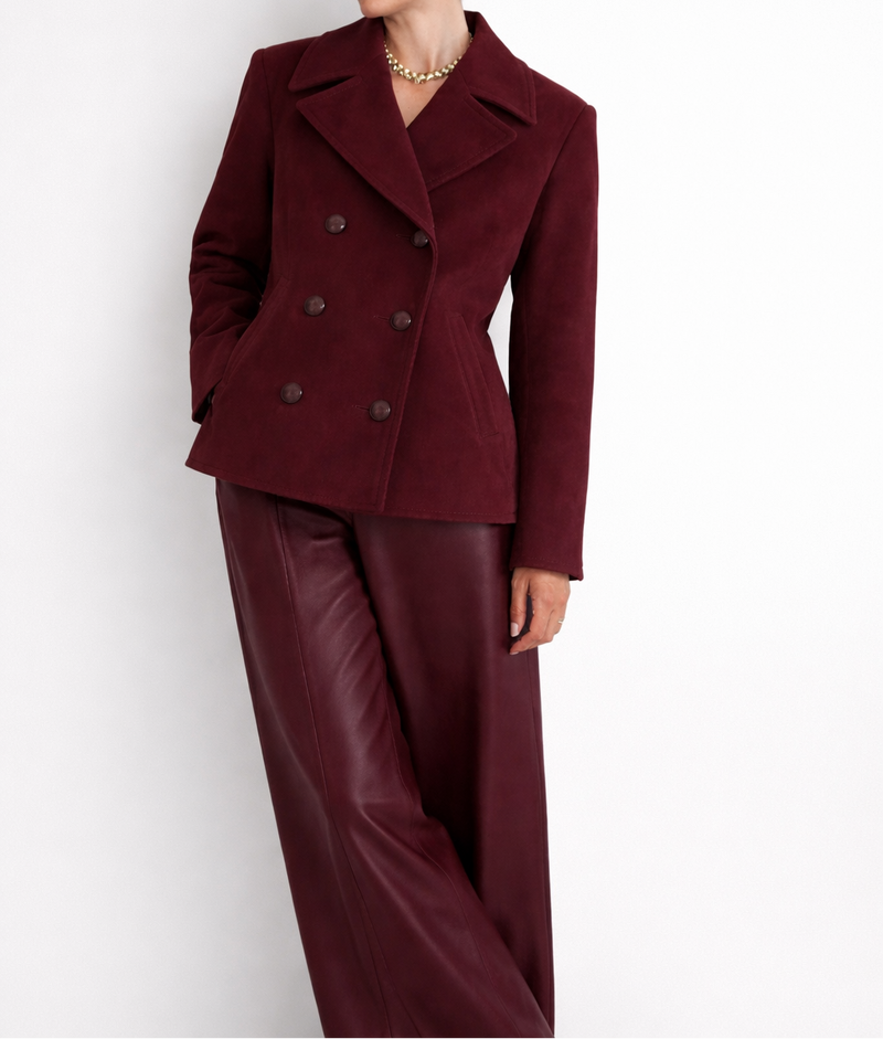 Woman wearing a burgundy coat and pants against a white background